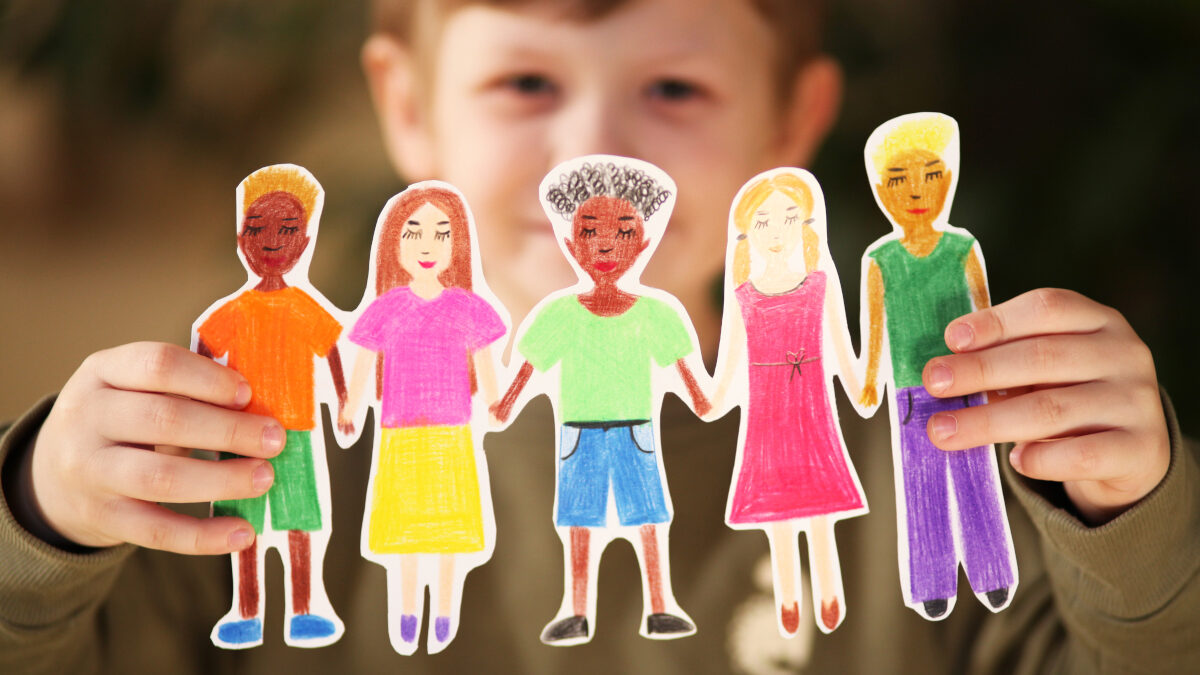 Niño sosteniendo guirnalda casera de papel de personas de diferentes etnias.