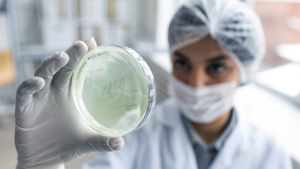 Blurred scientist holding petri dish with bacteria.